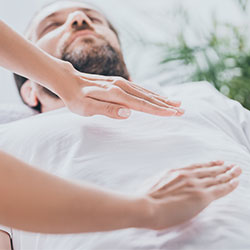 reiki masseuse holding hands over patients body