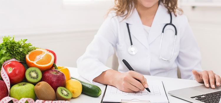 a female dietitian composing a diet plan on a clipboard with fruit beside her