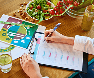 a dietitian doing meal planning at a table with food on it, using a colorful template