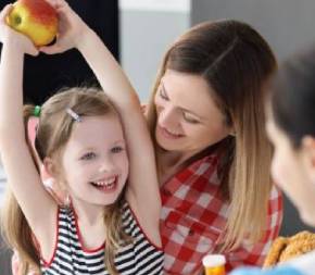 child-holding-apple-smiling-at-pediatric-nutritionist