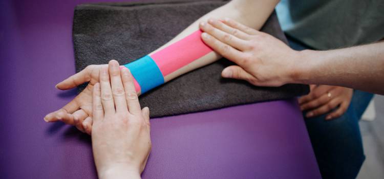 a kinesiologist applying pressure on clients taped forearm