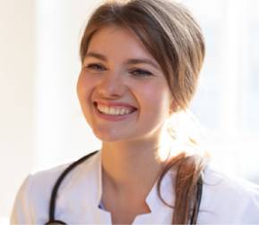 a smiling holistic nurse wearing a white coat with a stethoscope around her neck
