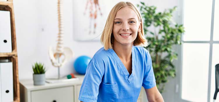 female physical therapist sits in office in front of spinal model