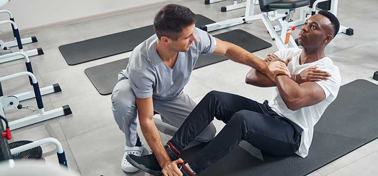 male pt helps patient hold crunch in correct form